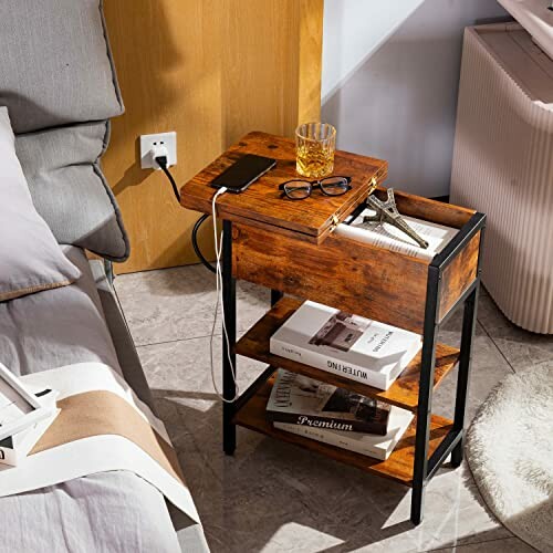 Wooden bedside table with books, drink, and glasses.