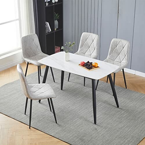 Modern dining table with four chairs and a fruit centerpiece.