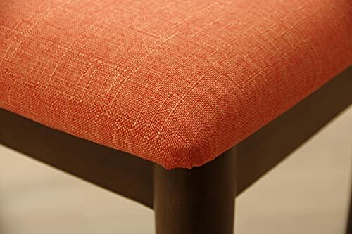 Close-up of an orange fabric chair corner with wooden legs.