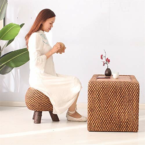 Woman sitting on rattan stool with a wicker table and vase